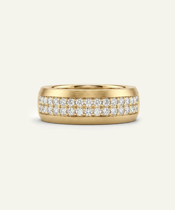 A men's wide yellow gold two-row diamond band ring on a light cream background.
