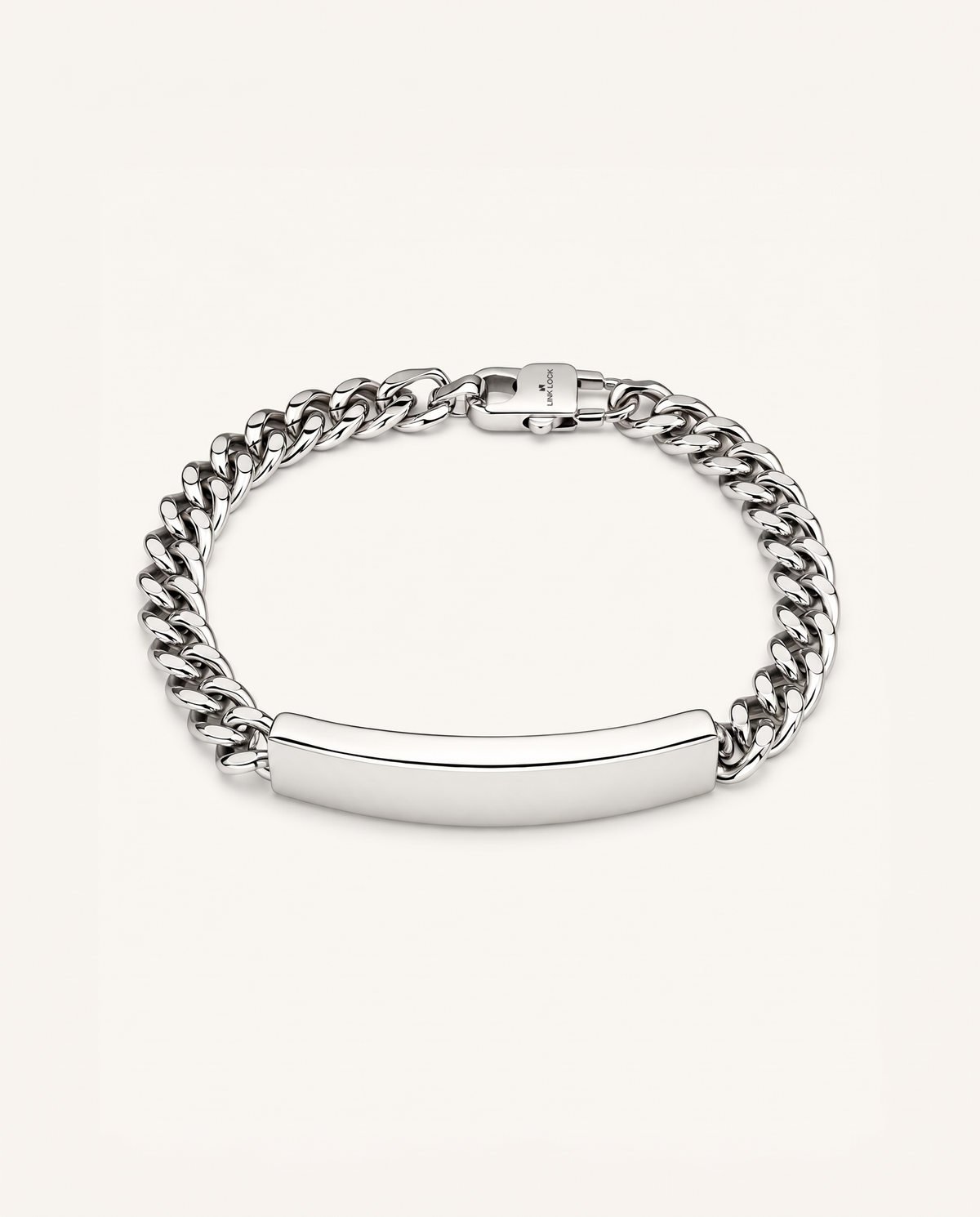 A silver-toned metal bracelet featuring a curb chain and a smooth, polished ID bar clasp, shown on a light cream background.