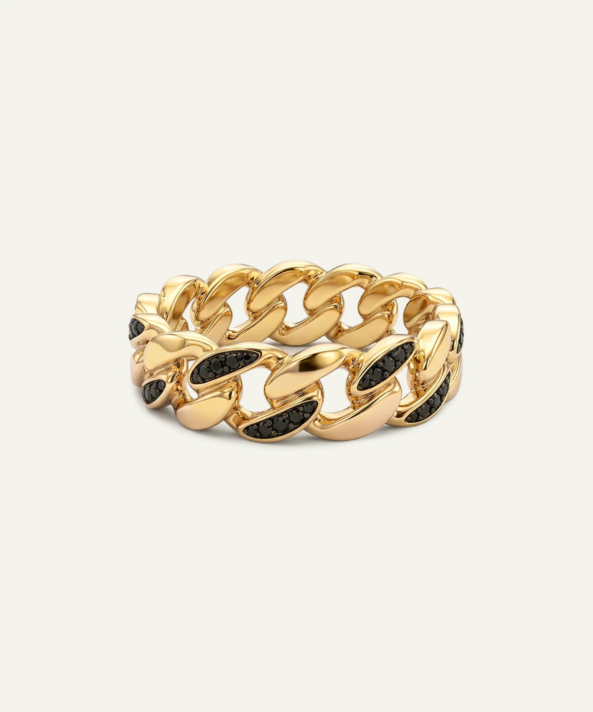 A men's yellow gold Cuban link band ring set with black round-cut gemstones on a light cream background.