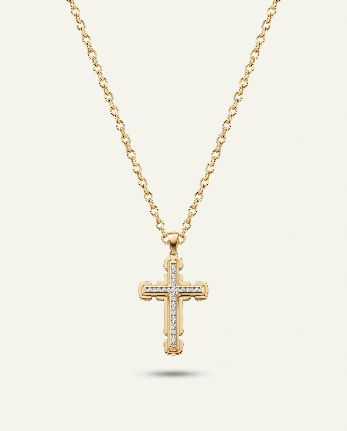 A gold cross pendant necklace with small clear stones set along the arms, hanging from a delicate gold chain against a light cream background.