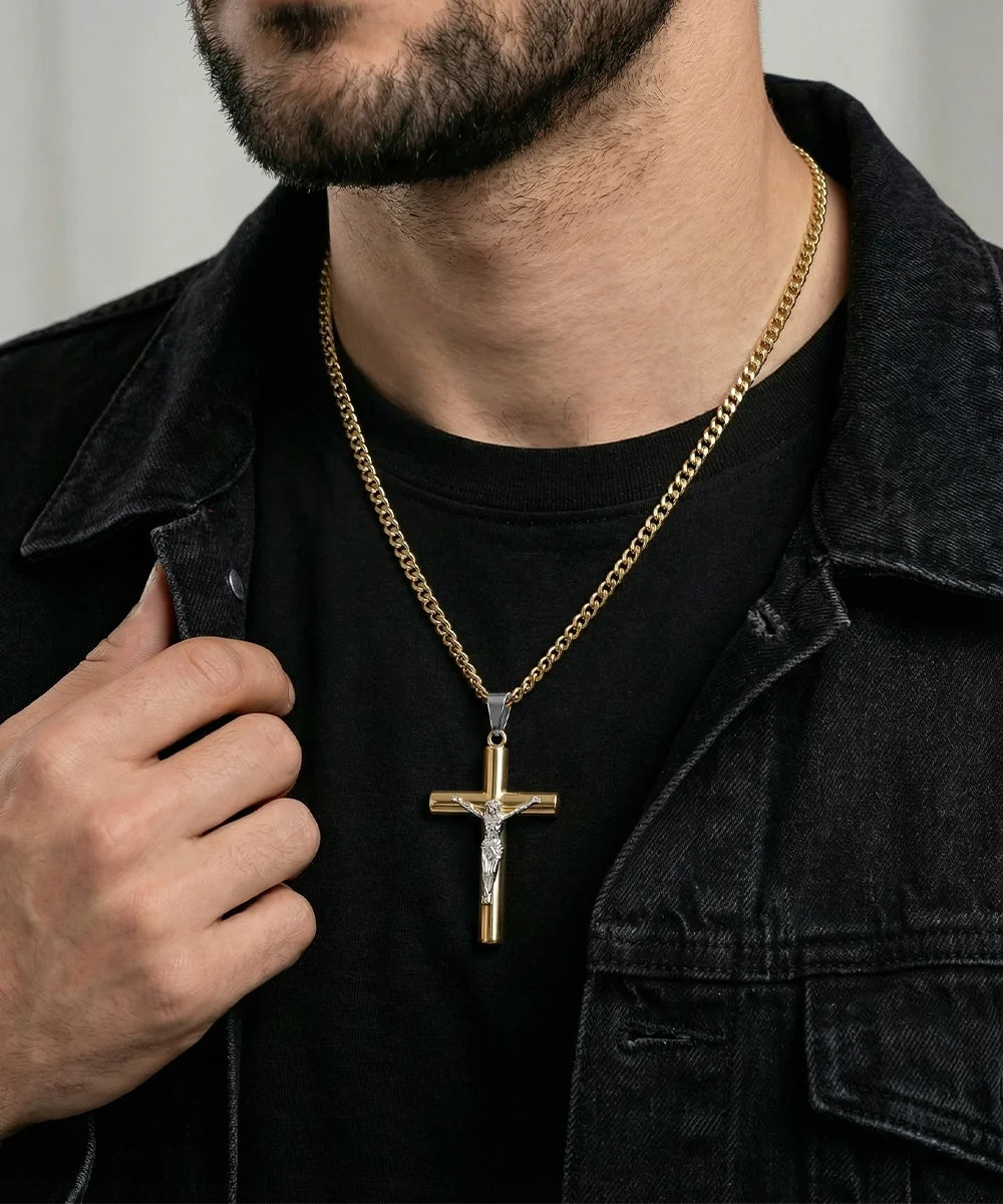 Men's lifestyle view of a gold crucifix cross pendant necklace with a silver-toned Jesus figure, worn over a black t-shirt and dark denim jacket.