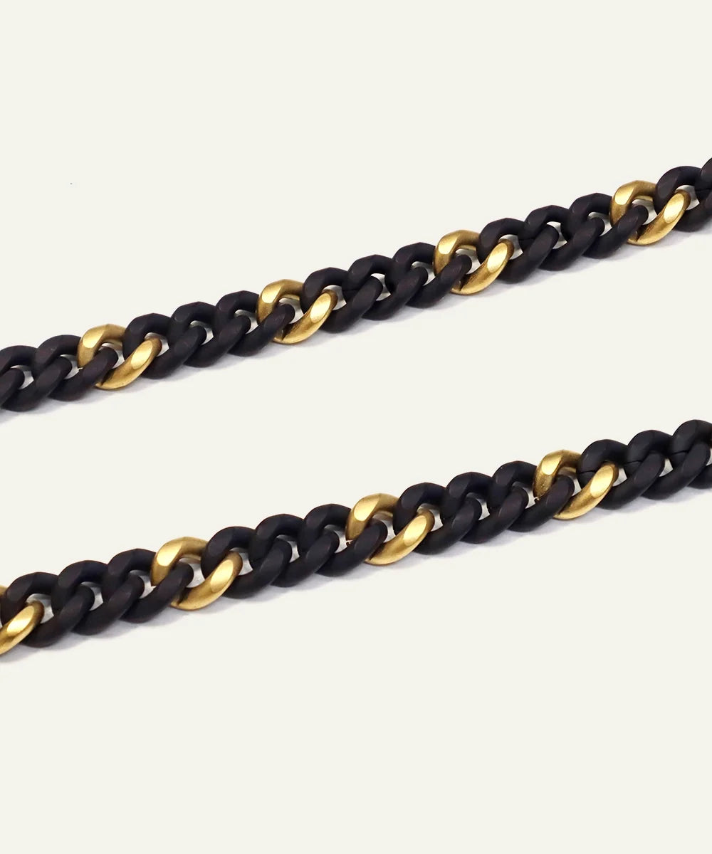 Close-up of two-tone black and gold curb chain links